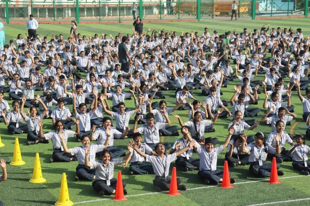 Students practising meditation for students outdoors in a school field, sitting peacefully in rows to improve focus and mental clarity.